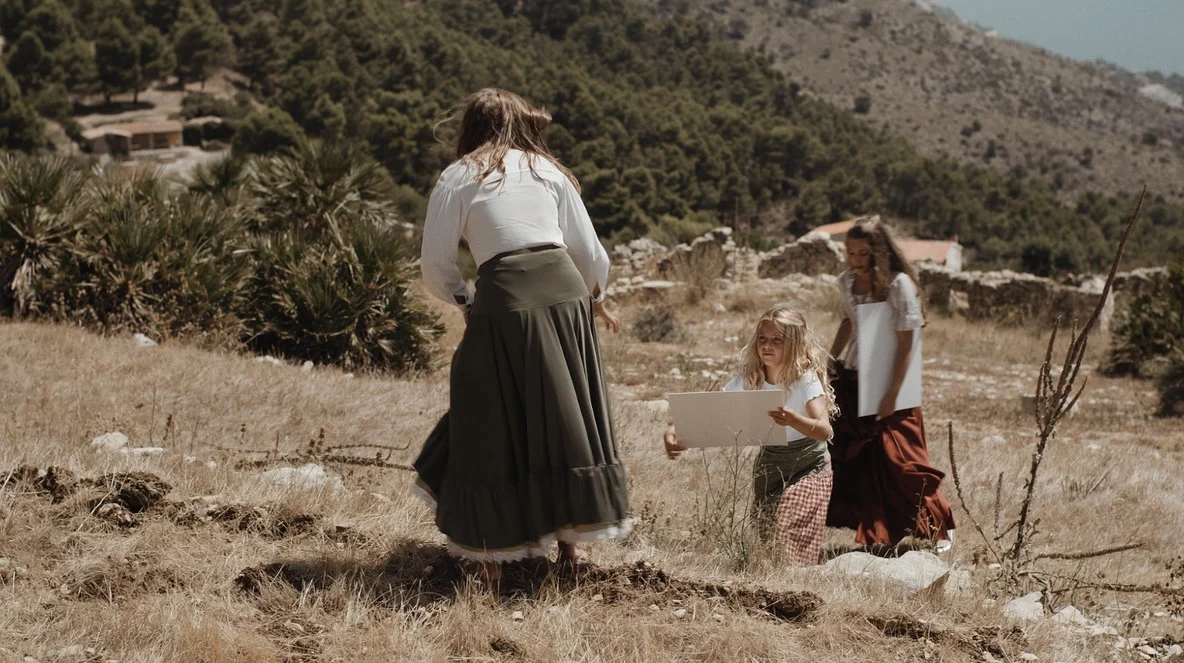 Tres mujeres con un lienzo en un paisaje de montaña