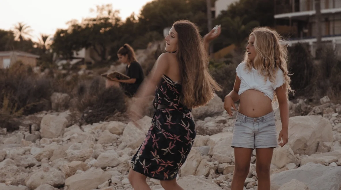 Dos mujeres junto al mar, con otra escribiendo al fondo